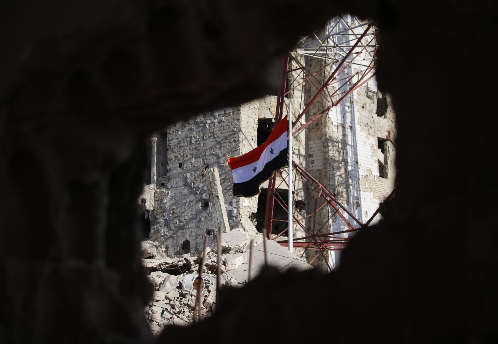 The Syrian national flag rises in the midst of damaged buildings in Daraa-al-Balad, an opposition-held part of the southern city of Daraa, on July 12, 2018. Syria's army entered rebel-held parts of Daraa city , state media said, raising the national flag 