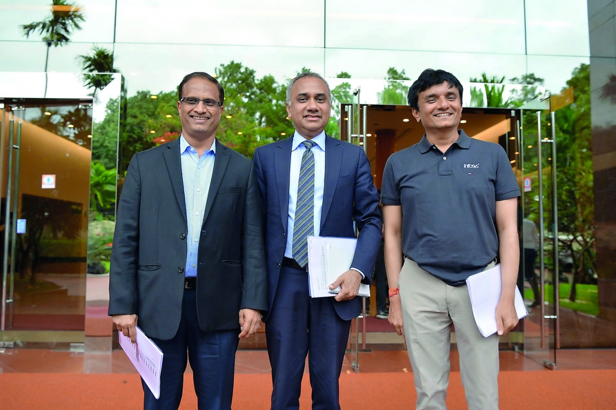 Indian CEO and Managing Director of Infosys Salil Parekh (C), flanked by Chief Financial Officer M.D. Ranganath (R) and Chief Operating Officer U.B. Pravin Rao pose for a photograph in front of the Infosys headquarters prior to a press conference held in 