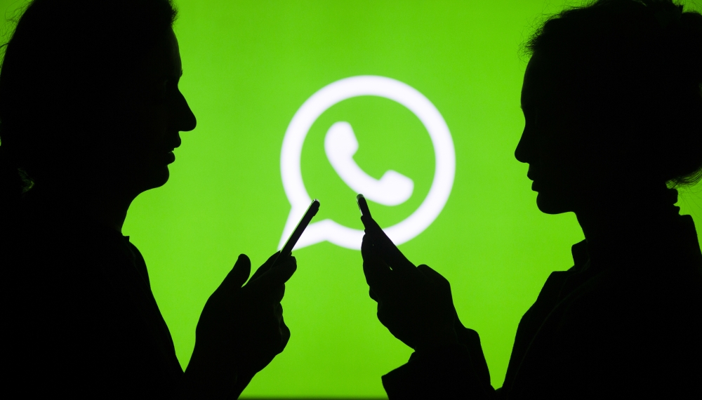 Silhouettes of people holding mobile phones in front of the logo of WhatsApp application in Ankara, Turkey on July 18, 2018. ( Aytaç Ünal - Anadolu Agency )