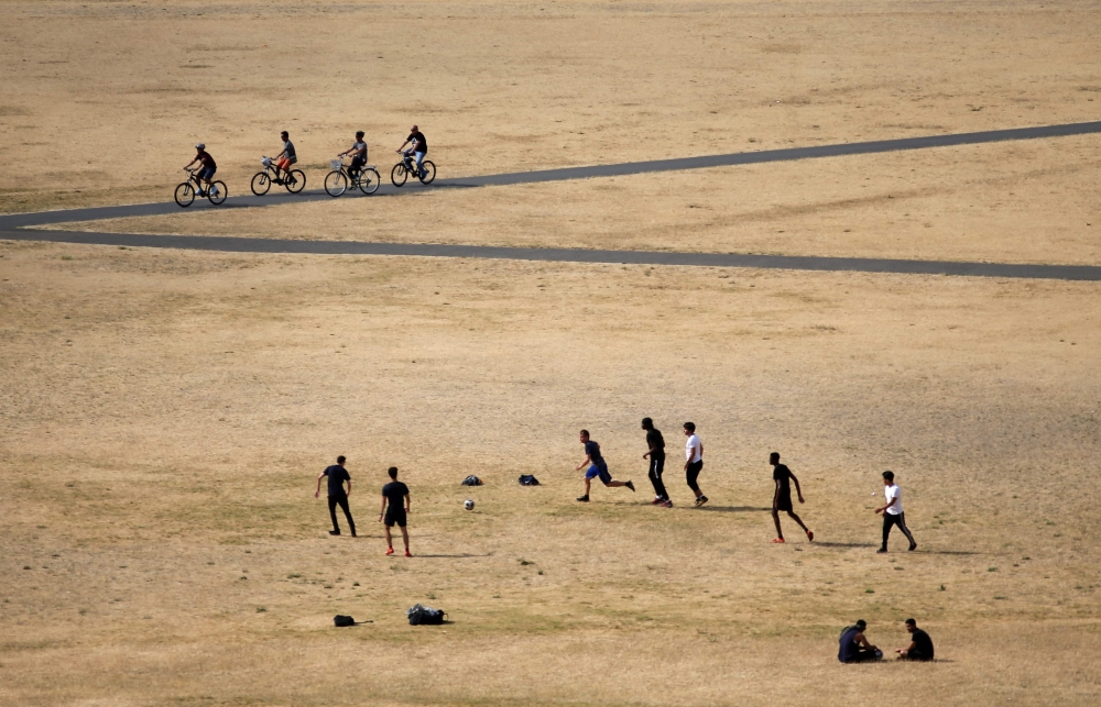 Visitors to Greenwich Park play football on the dry brown grass in London on July 23, 2018. AFP / Daniel Leal-Olivas