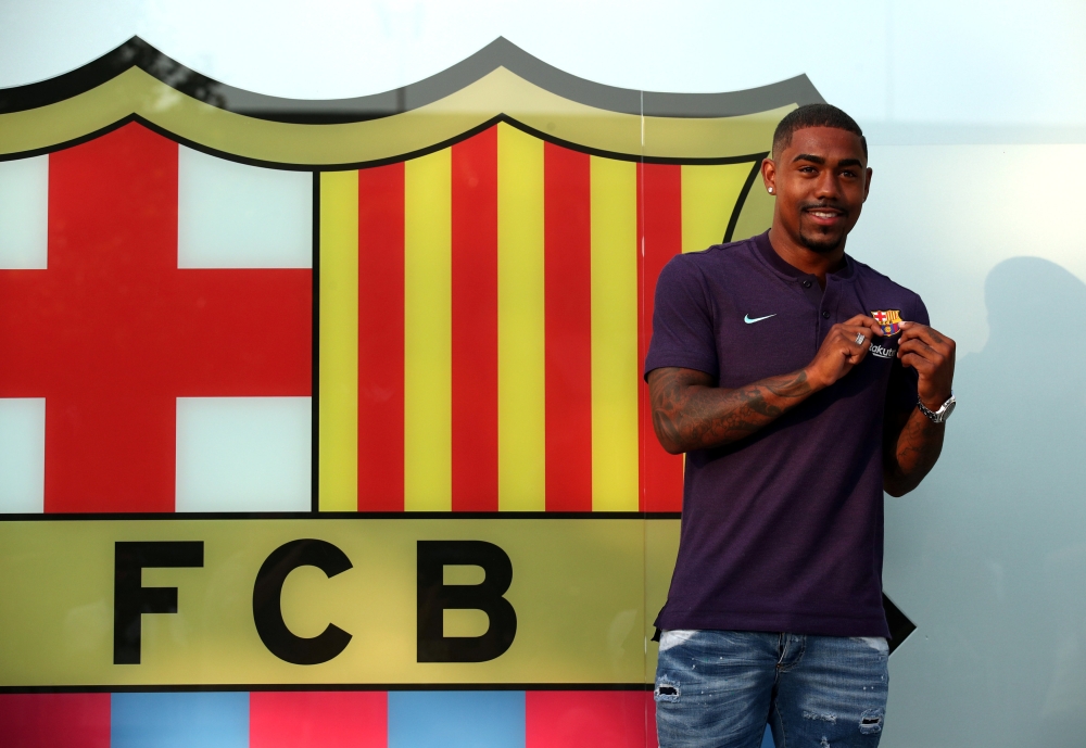 Brazilian soccer player Malcom Filipe Silva de Oliveira poses in front of a FC Barcelona logo at their offices next to Camp Nou stadium in Barcelona, Spain July 24, 2018. REUTERS/Albert Gea
