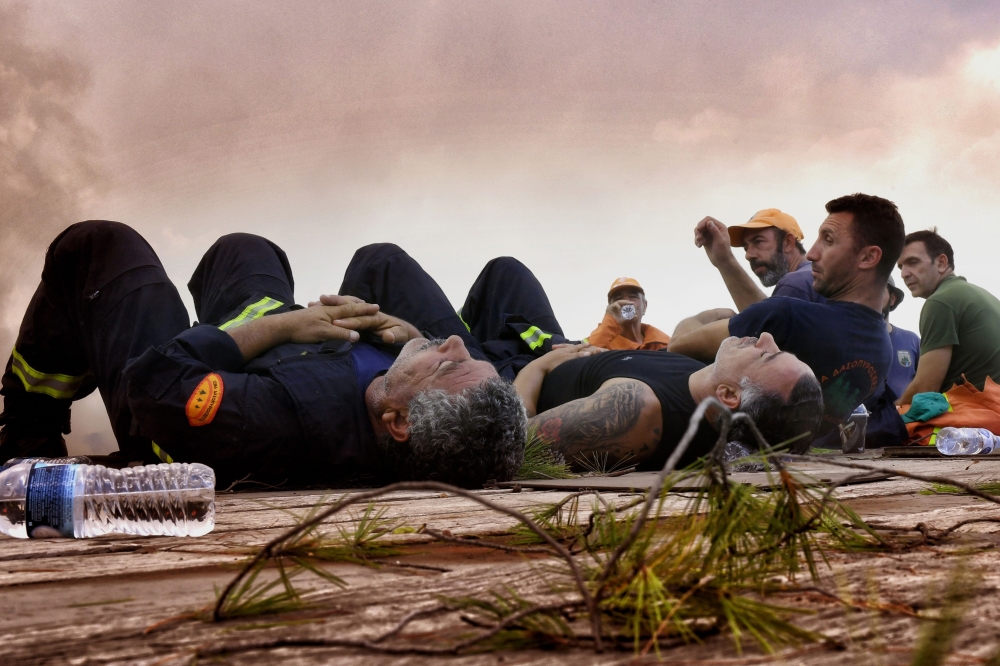 Firefighters from Cyprus rest during a wildfire at the village of Kineta, near Athens, on July 25, 2018.  AFP / Valerie Gache