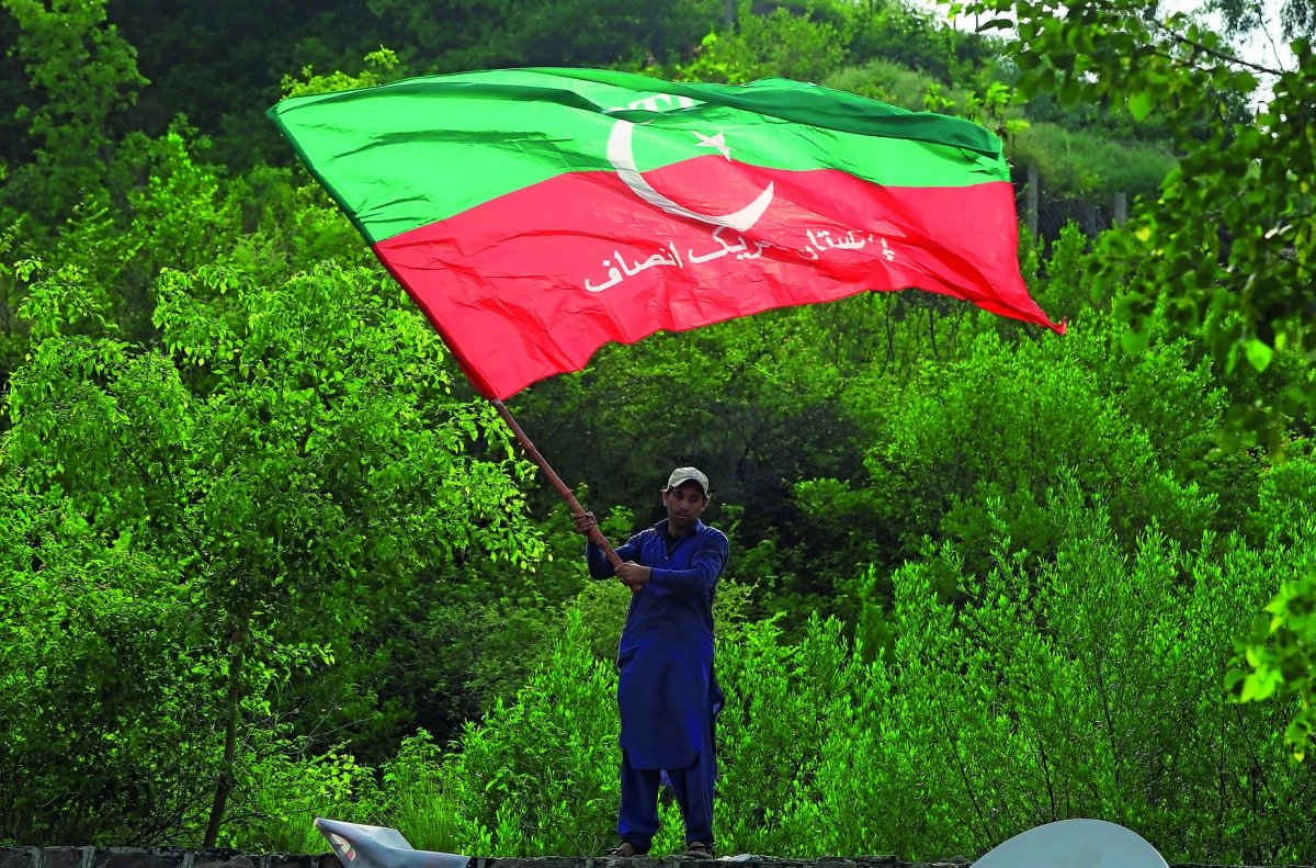 A supporter of cricket star-turned-politician Imran Khan, chairman of Pakistan Tehreek-e-Insaf (PTI), waves a party flag as he celebrates outside his residence in Islamabad, Pakistan, a day after polling in the general election, July 26, 2018. Reuters/Fai