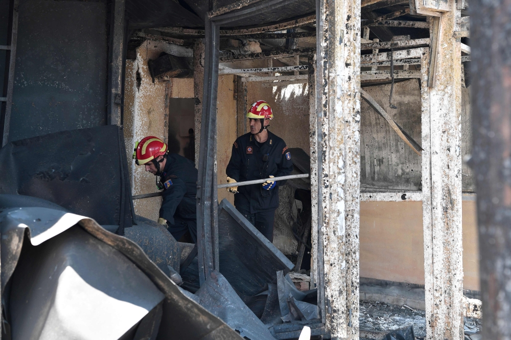 Firemen investigate inside a burnt out property at the seaside resort of Mati, in the eastern Attica region after the deadly fires swept the area earleir in the week on July 27, 2018.  AFP / Louisa Gouliamaki