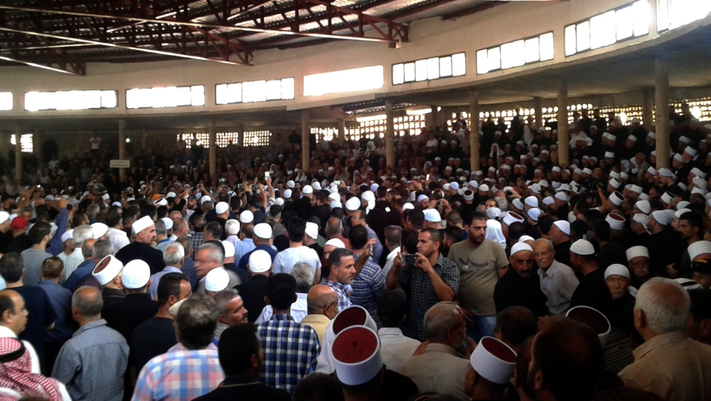 A handout picture released by the official Syrian Arab News Agency (SANA) shows Syrians during a mass funeral of yesterday's suicide attacks victims in the southern city of Sweida on July 26, 2018. (AFP / SANA)