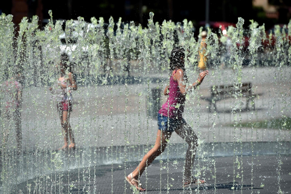 Children cool off in a fountain in Albi, southern France, on August 5, 2018, as a heatwave in Europe continues. AFP / Remy Gabalda 