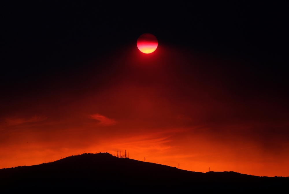 The sun sets under a cloud of smoke caused by a wildfire fanned by strong winds on the island of Evia, in Athens, Greece, August 12, 2018. Reuters/Yannis Behrakis