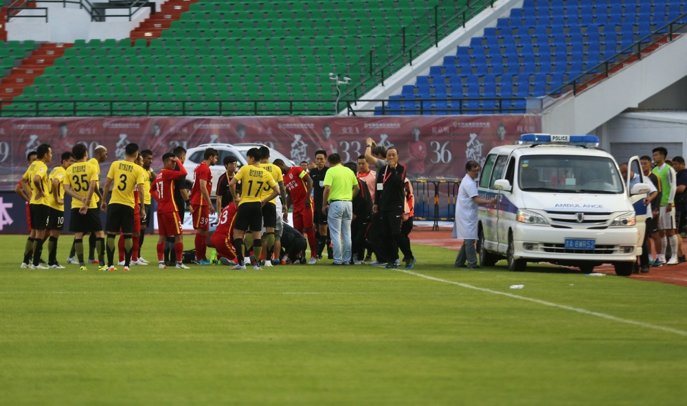 This photo taken on August 11, 2018 shows Wang Shouting (C-on ground), a player for Chinese club Changchun Yatai, receiving medical attention after an injury as medical staff (R) try to open the door of an ambulance during their Chinese Super League footb