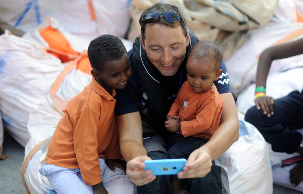 Migrants play with a member of the crew on board the MV Aquarius rescue ship, run by SOS Mediterranee organisation and Doctors Without Borders, during a search and rescue (SAR) operation in the Mediterranean Sea, off the Libyan Coast, August 12, 2018.  12