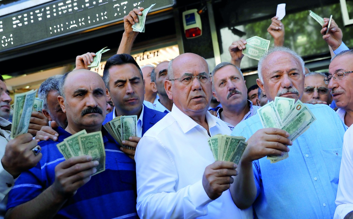 Businessmen holding U.S. dollars stand in front of a currency exchange office in response to the call of Turkish President Tayyip Erdogan on Turks to sell their dollar and euro savings to support the lira, in Ankara, Turkey August 14, 2018. Reuters/Umit B