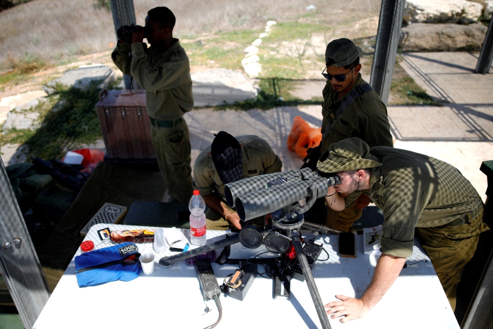 Israeli soldiers looks through binoculars at an observation post near the Israeli side of the Israel - GAZA border, Israel August 15, 2018. REUTERS/Amir Cohen 