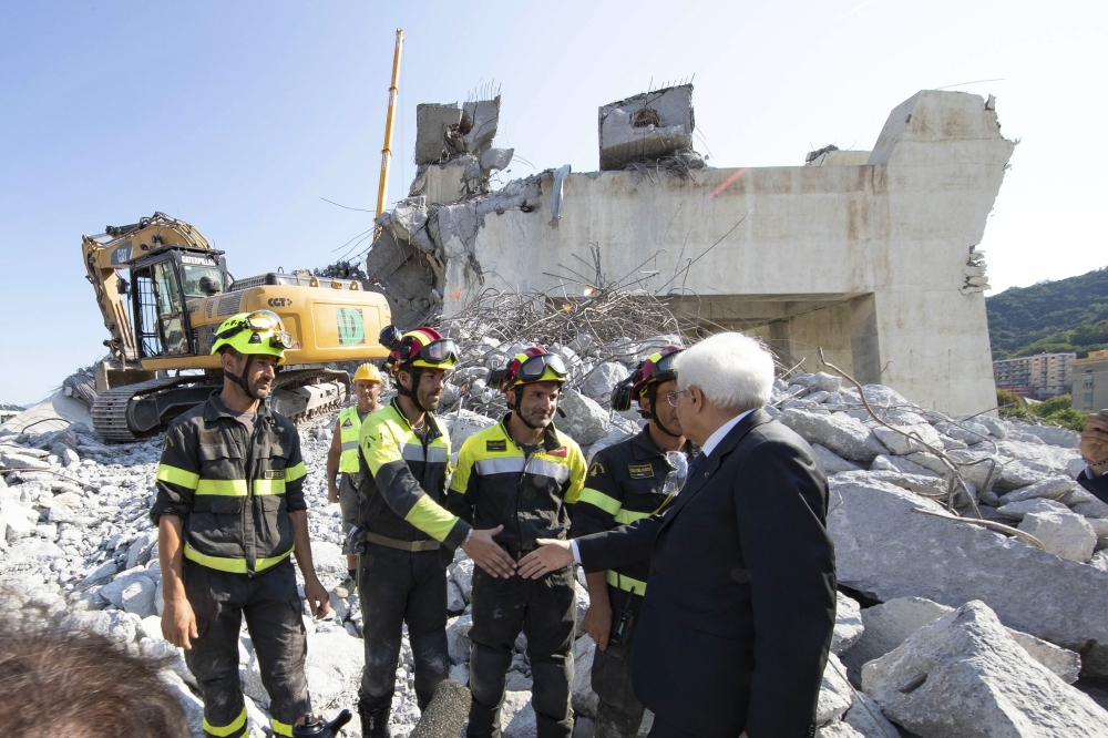 A handout photo made available by the Quirinal Press Office shows Italian President Sergio Mattarella (R) during his visit to the site of the highway-bridge-collapse disaster, before attending the State funeral of the victims, in Genoa on August 18, 2018.