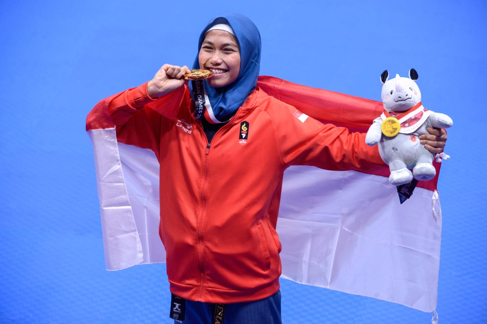 Indonesia's Defia Rosmaniar poses with her gold medal after defeating Iran's Marjan Salahshouri to win the taekwondo women's individual poomsae final at the 2018 Asian Games at Jakarta on August 19, 2018. / AFP / CHAIDEER MAHYUDDIN