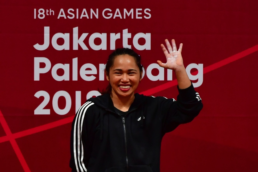 Hidilyn Diaz of Philippines celebrate at the podium during the victory ceremony for the women's 53kg weightlifting event during the 2018 Asian Games in Jakarta on August 21, 2018. / AFP / MONEY SHARMA