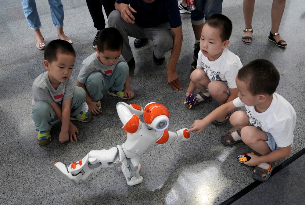 A boy touches a robot as it performs Taiji, a traditional form of Chinese martial arts, at the World Robot Conference (WRC) in Beijing, China August 17, 2018. Reuters/Jason Lee