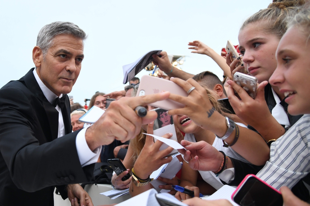 US actor and director George Clooney signs autographs before the premiere of the movie 