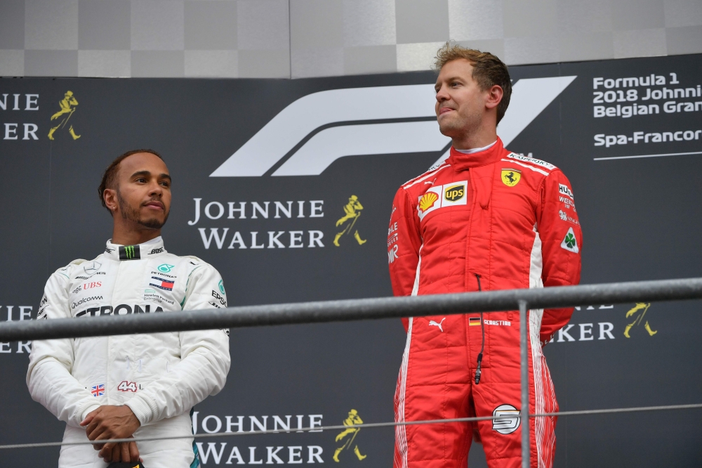 Winner Ferrari's German driver Sebastian Vettel (R) celebrates on the podium next to second placed Mercedes' British driver Lewis Hamilton after the Belgian Formula One Grand Prix at the Spa-Francorchamps circuit in Spa on August 26, 2018. / AFP / EMMANUE