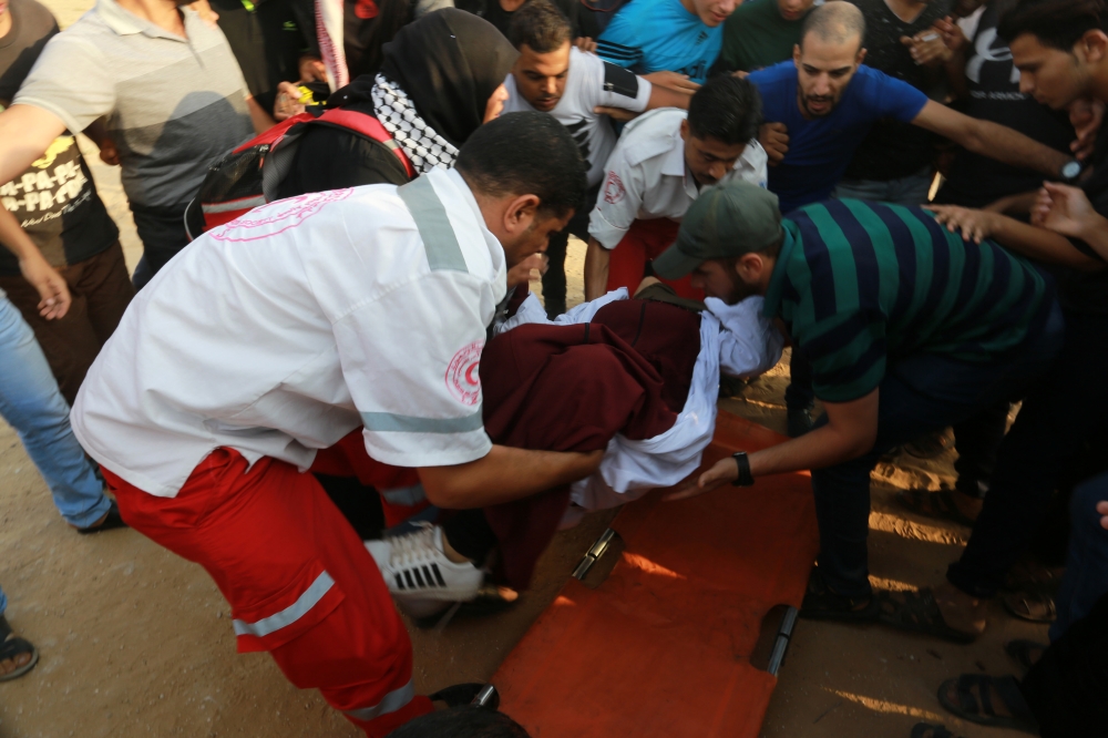Paramedics help a female health officer who was injured as Israeli forces intervene to disperse Palestinian protestors on the 23rd Friday near Gaza-Israel border in Rafah, Gaza on August 31, 2018. ( Abed Rahim Khatib - Anadolu Agency )