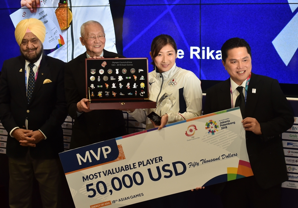 Japan's swimmer Ikee Rikako (2nd R), who won six gold medals during the games, poses for a photo with a cheque for 50,000 USD after being named as the 