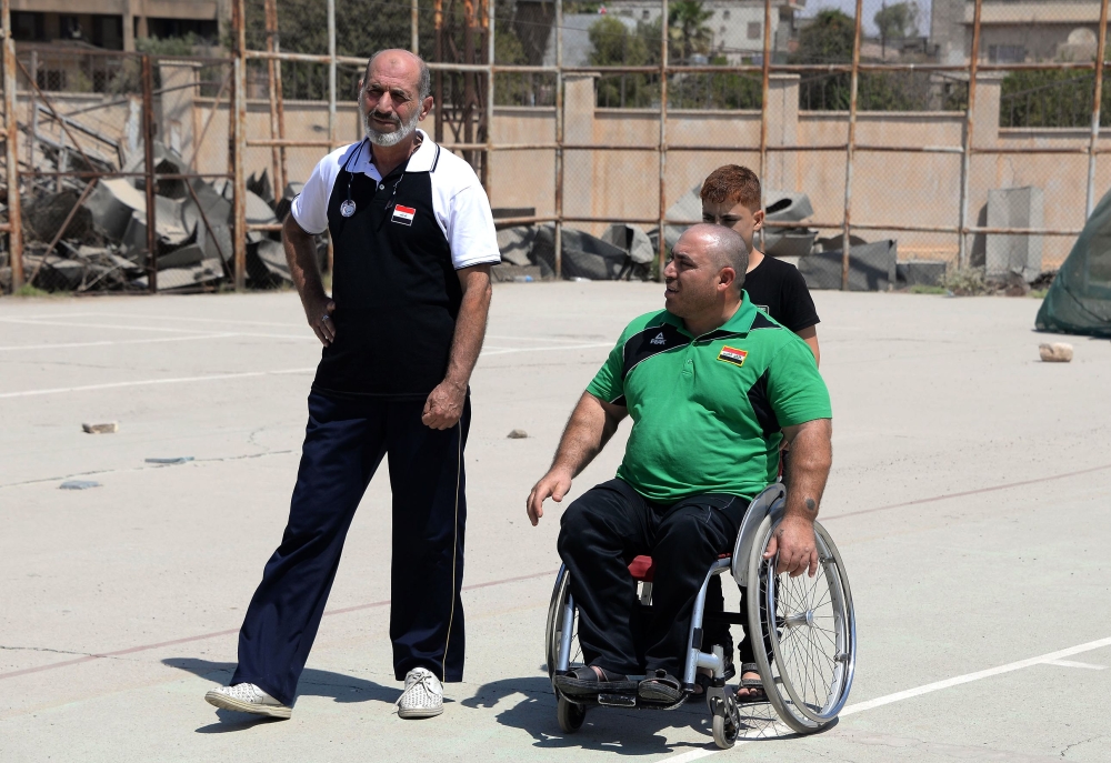 Iraqi paralympic weightlifter Thaer al-Ali (R) speaks to his trainer Tamer Ghanem, in the northern city of Mosul on August 25, 2018. AFP / Zaid AL-OBEIDI
