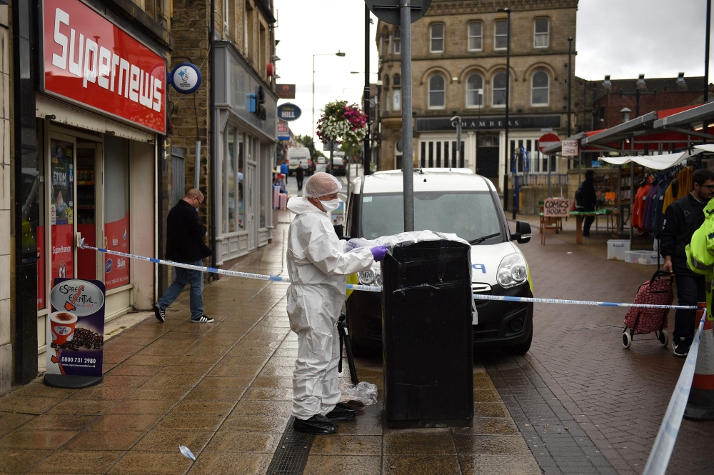 A police forensics officer looks for evidence inside a cordon in Peel Square, following a stabbing incident in the centre of Barnsley, northern England on September 8, 2018.   AFP / Oli SCARFF