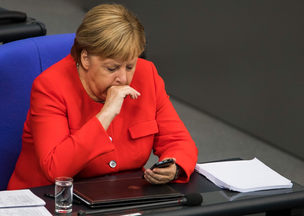 German Chancellor Angela Merkel looks at her phone during a sitting of the Bundestag, Germany's lower house of parliament in Berlin on September 12, 2018. / AFP / Odd ANDERSEN