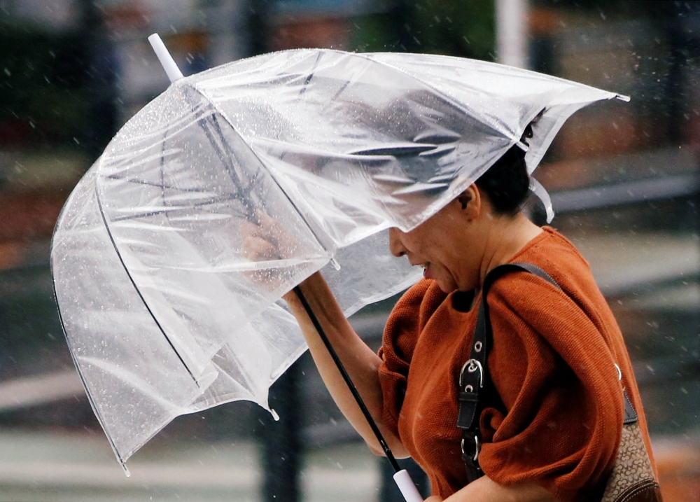 A passerby, using an umbrella, struggles against a heavy rain and wind as Typhoon Jongdari approaches mainland in Tokyo, July 28, 2018. (Reuters / Issei Kato) 
