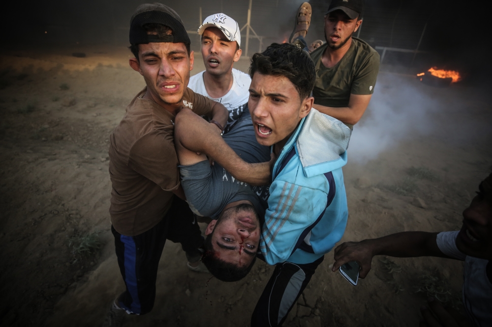 Protesters carry a Palestinian shot and wounded by Israeli troops on the 25th Friday of 