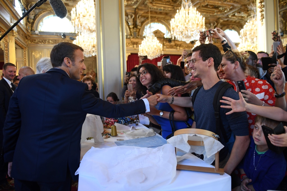 French President Emmanuel Macron (L) shakes people's hands as visitors are allowed access to the Elysee Palace in Paris on September 15, 2018, as part of France's Heritage Days. / AFP / POOL / Anne-Christine POUJOULAT