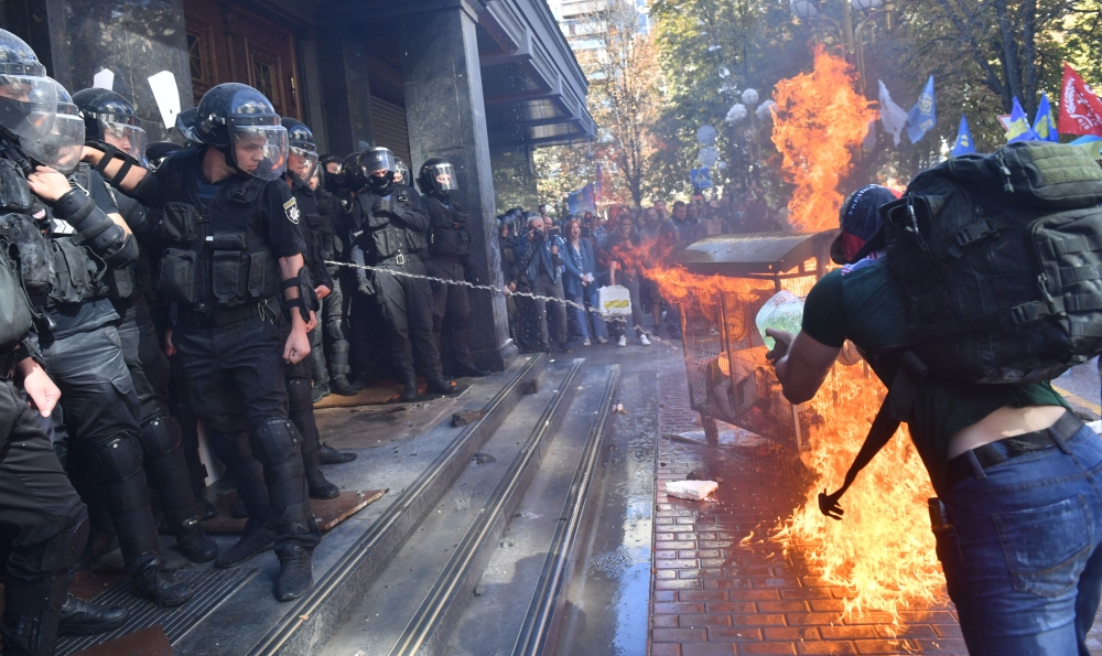 Activists of Ukrainian far-right groups burn a fire during their clashing with riot police in front of the Prosecutor General's Office in Kiev on September 17, 2018 as the Ukrainian authorities extradited a Russian citizen wanted by Moscow as a suspected 