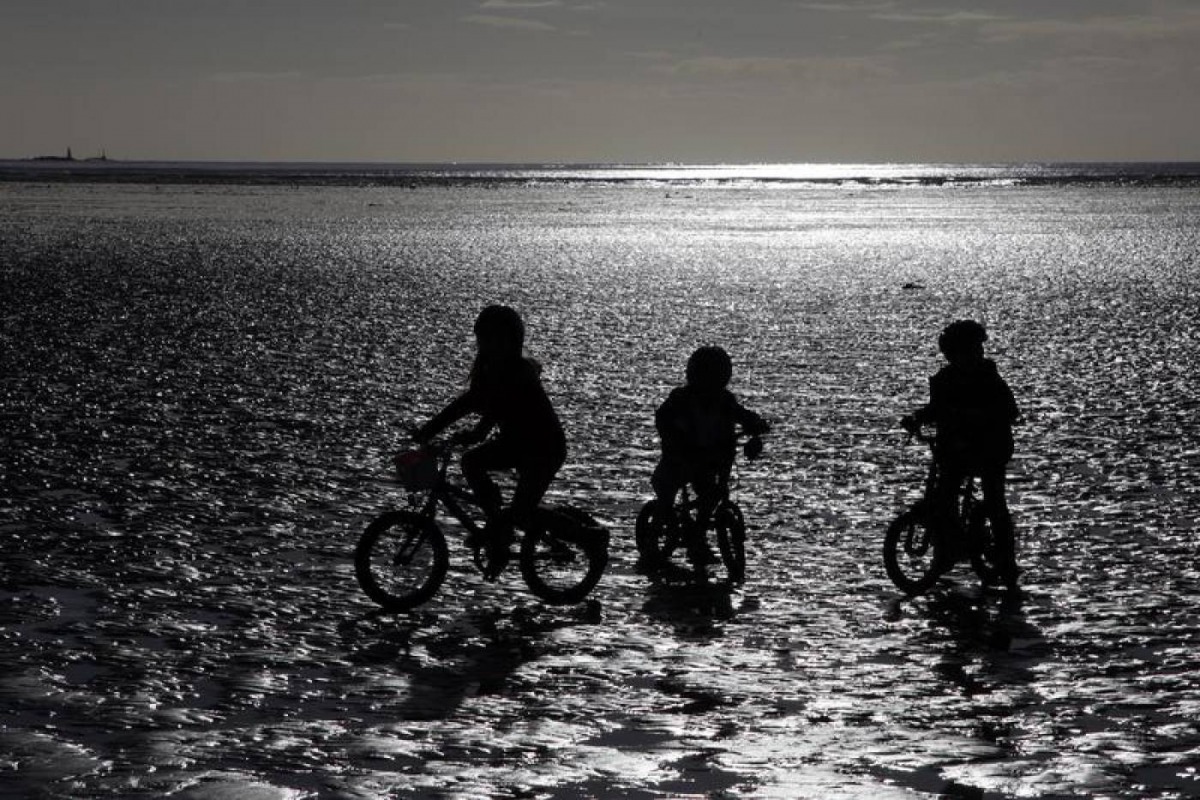 Children ride their bike along the beach during low tide near St Helier, Jersey November 11, 2012. Reuters/Stefan Wermuth