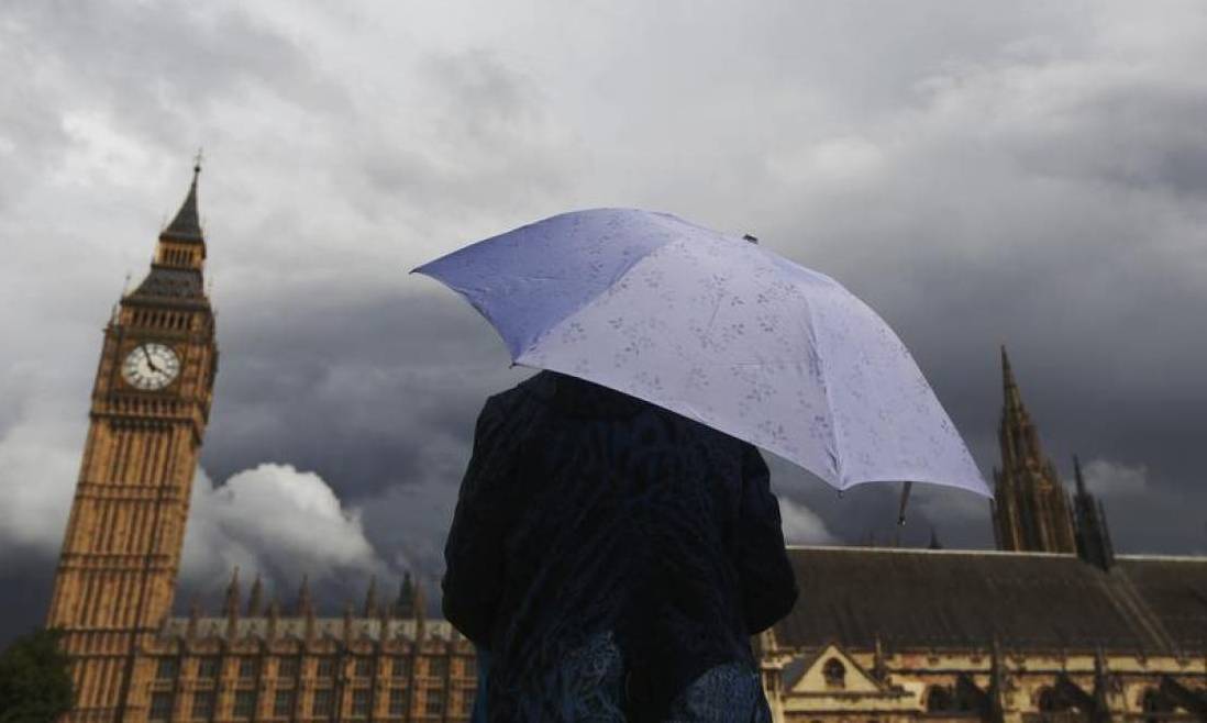 A woman looks towards dark clouds over the Houses of Parliament in central London, August 11, 2014. (Reuters/Luke MacGregor) 