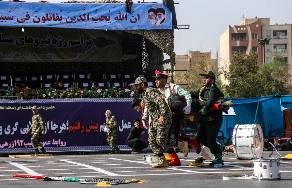Iranian soldiers carrying away an injured comrade at the scene of an attack on a military parade that was marking the anniversary of the outbreak of its devastating 1980-1988 war with Saddam Hussein's Iraq. AFP / MORTEZA JABERIAN
