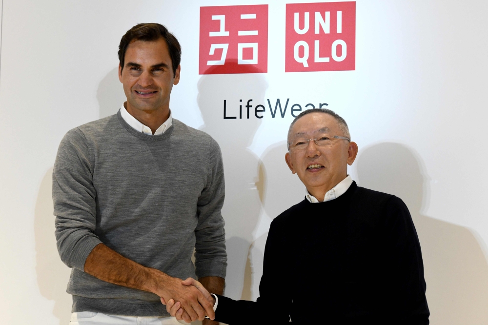 Switzerland's tennis player Roger Federer (L) shakes hands with Tadashi Yanai, founder and president of Fast Retailing, known as the UNIQLO brand, during the photo session of a press conference at the Fast Retailing headquarters in Tokyo on October 2, 201