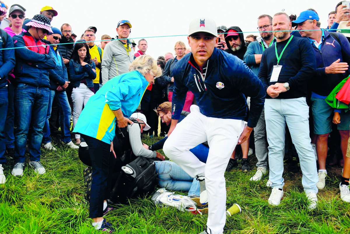 US golfer Brooks Koepka (R) reacts next to an injured spectator who fell during the fourball match on the first day of the 42nd Ryder Cup at Le Golf National Course at Saint-Quentin-en-Yvelines, south-west of Paris on September 28, 2018. AFP / Franck Fife