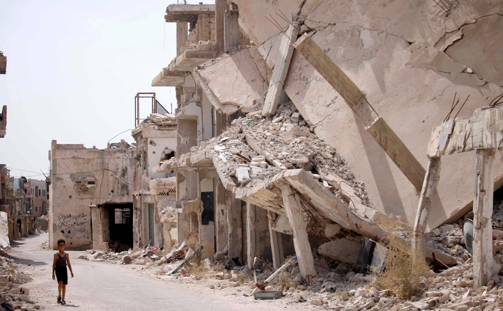 A Syrian child walks past the rubble of destroyed buildings in an opposition-held neighbourhood of the southern city of Daraa on October 2, 2018. / AFP / Mohamad ABAZEED