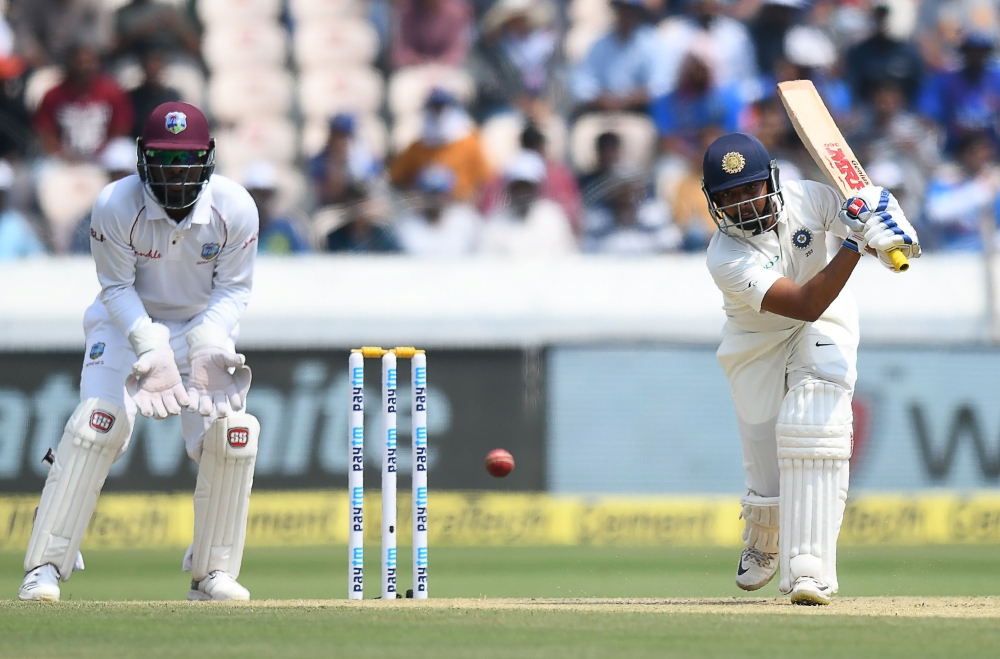 Indian cricketer Prithvi Shaw (R) plays a shot during the second day's play of the second Test cricket match between India and West Indies at the Rajiv Gandhi International Cricket Stadium in Hyderabad on October 13, 2018. GETTYOUT / AFP / NOAH SEELAM 