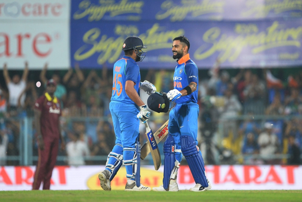 Indian batsman and team captain Virat Kohli (R) celebrates with his teammate Rohit Sharma after completing his century (100 runs) during the first one day international (ODI) cricket match between India and West Indies at Barsapara Cricket Stadium in Guwa