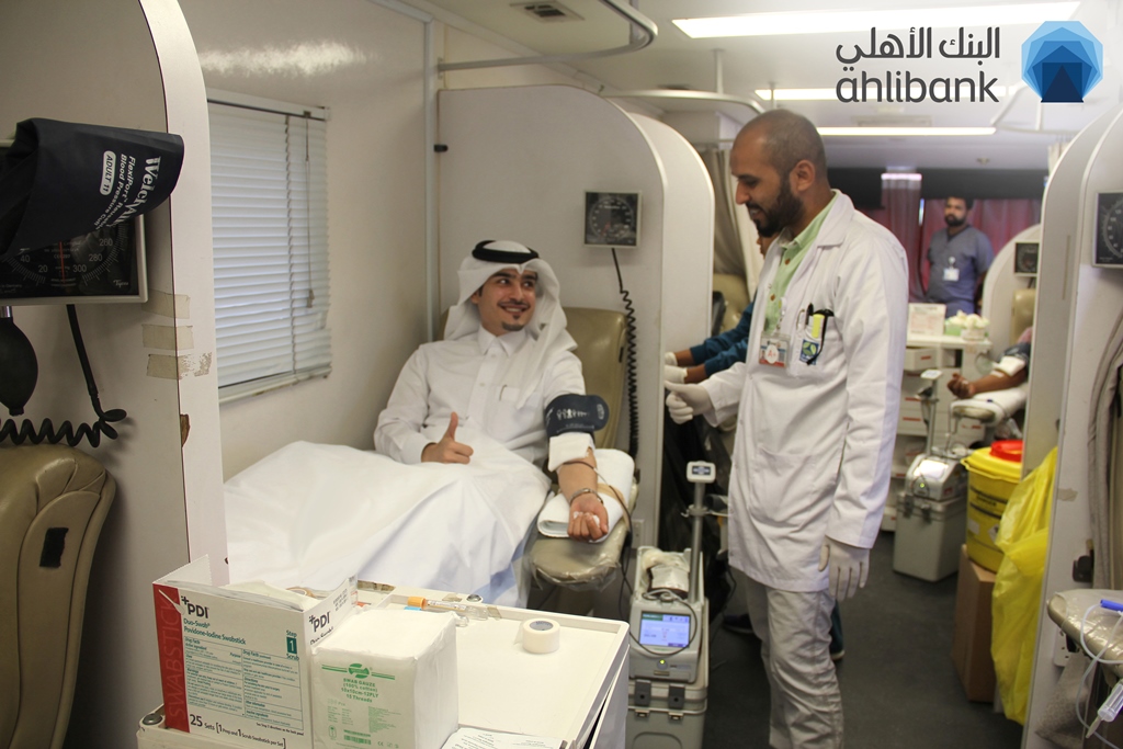 A young man donating blood during an Ahlibank blood donation campaign. 