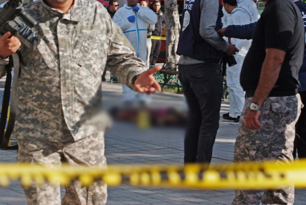 Police standing near the body of a suicide bomber who blew herself up near police vehicles in the centre of the Tunisian capital Tunis. / AFP / STRINGER
