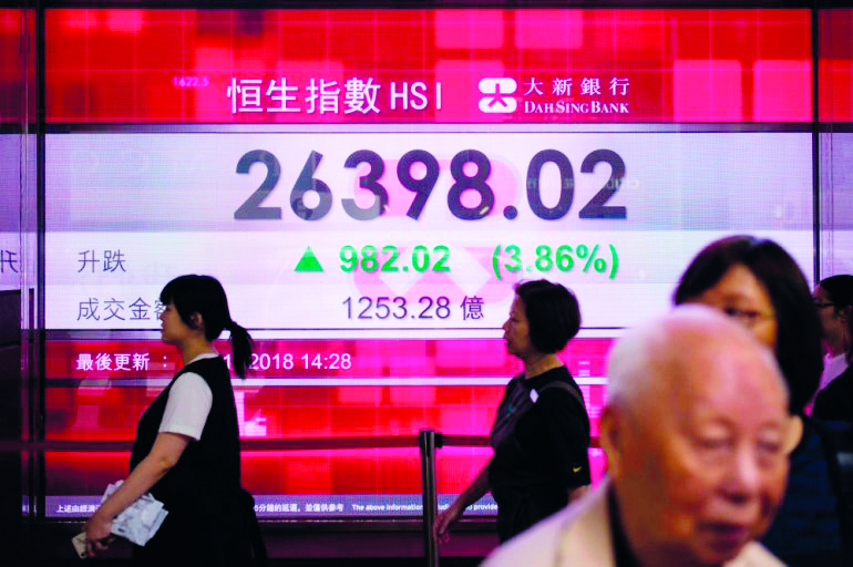 Pedestrians walk past a stocks display board that shows an increase in the Hang Seng Index in Hong Kong on November 2, 2018.  AFP / Anthony Wallace
