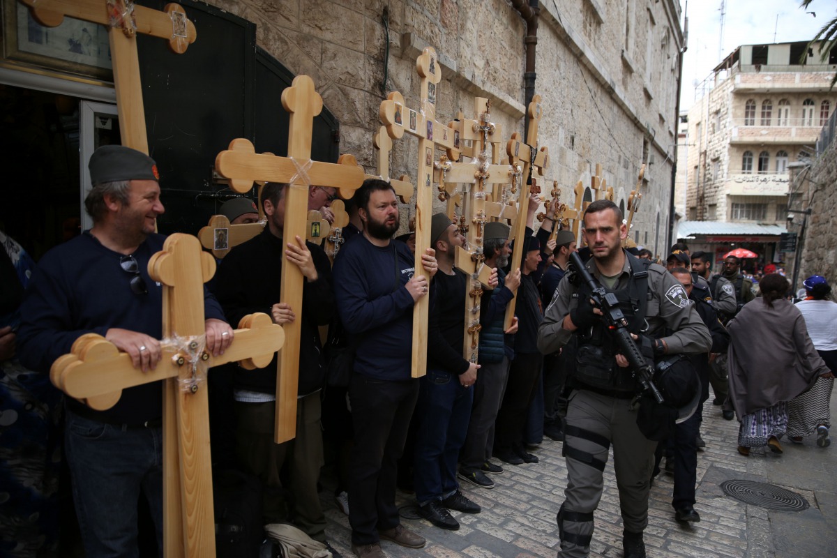 FILE PHOTO: Christian pilgrims carry wooden crosses along the path where Jesus walked, now known as the Via Dolorosa or the Way of Suffering on Good Friday in Jerusalem Old City on April 14, 2017. AFP/Gali Tibbon