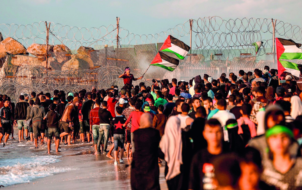 Palestinians protesters carry national flags as they gather during a demonstration calling for an end to the Israeli blockade on Gaza, on a beach in Beit Lahia near the maritime border with Israel, on November 5, 2018. AFP / Mahmud Hams

