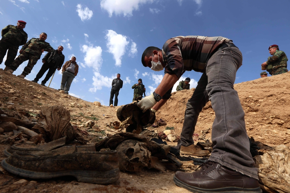 Members of the Yazidi minority search for clues that might lead them to missing relatives near the Iraqi village of Sinuni, in the northwestern Sinjar area In this file photo taken on February 03, 2015 . AFP / Safin Hamed
 