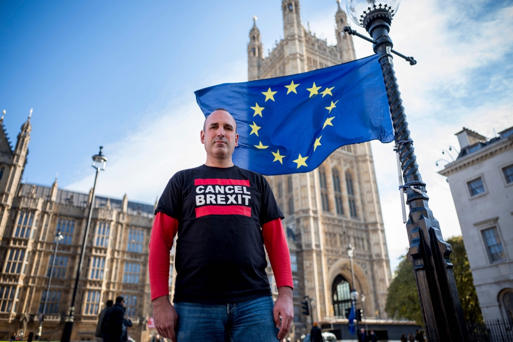 Spanish nurse and anti-Brexit campaigner Joan Pons Laplana poses for a photograph in front of an EU flag outside the Houses of Parliament in London on October 31, 2018. AFP / TOLGA AKMEN