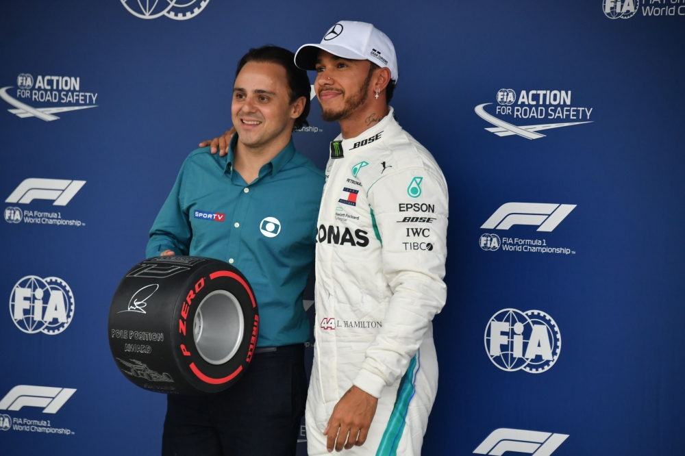 Mercedes' British driver Lewis Hamilton receives the pole position award from the Brazilian former driver Felipe Massa after taking the pole position for the F1 Brazil Grand Prix in the qualifying session at the Interlagos racetrack in Sao Paulo, Brazil o