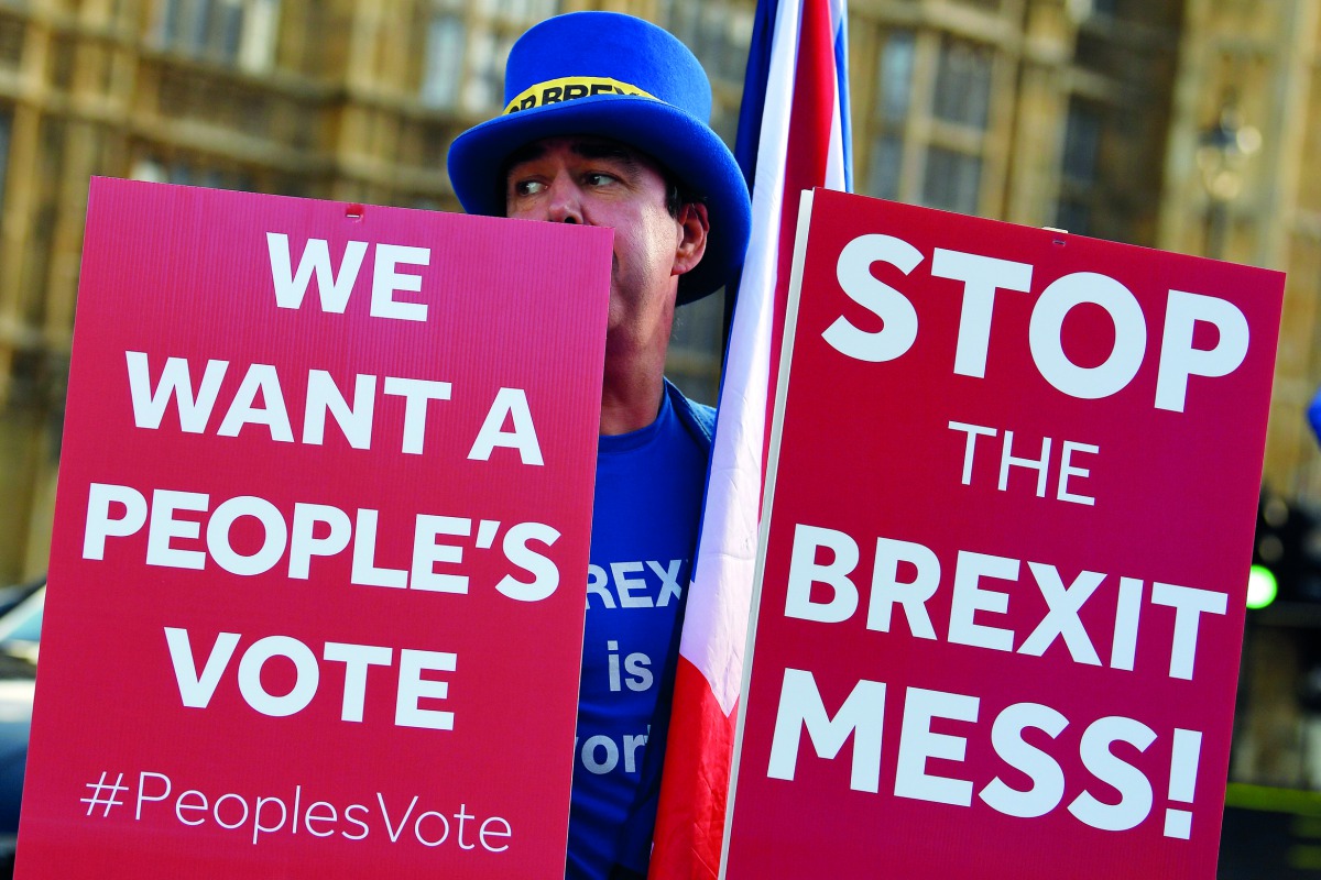 An anti-Brexit demonstrator holds placards outside the Houses of Parliament in London, Britain, November 13, 2018. Reuters/Toby Melville