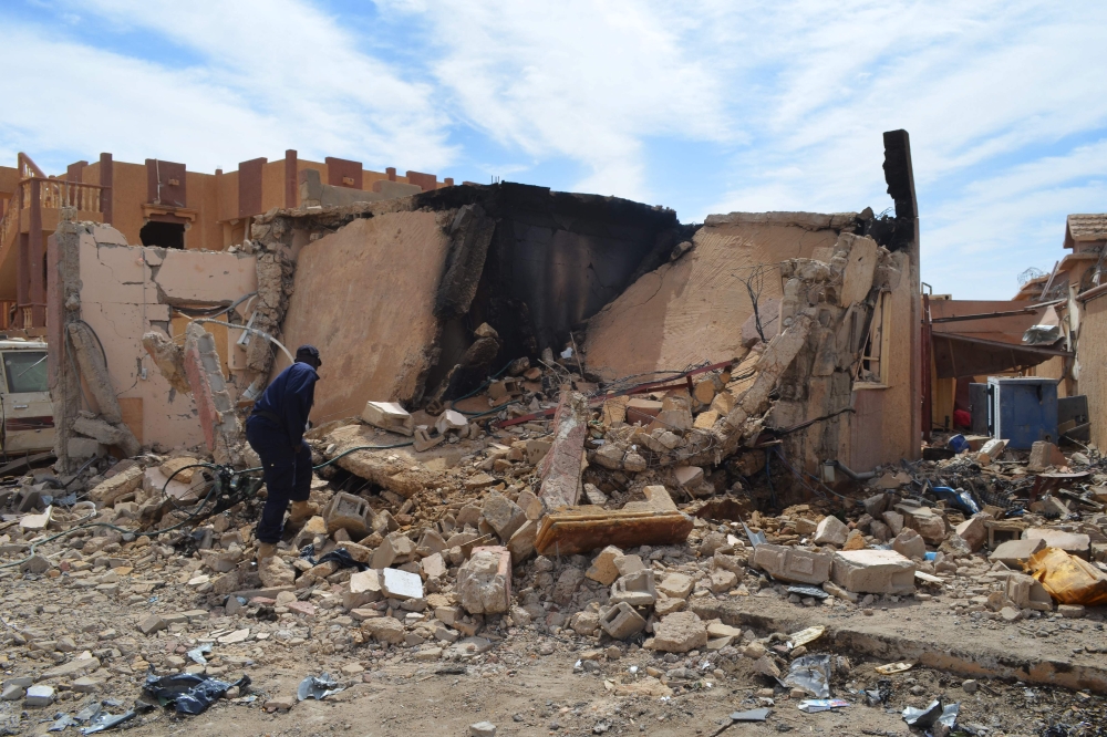 A Malian firefighter stands beside a destroyed house on November 13, 2018, in Gao, after a suicide car overnight, killing three people.  AFP