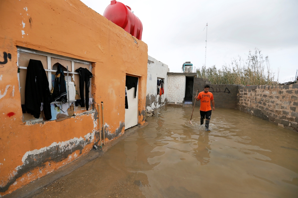 An Iraqi man cleans his house after heavy rainfall in al-Aziziyah, Iraq November 25, 2018. REUTERS/Khalid al-Mousily