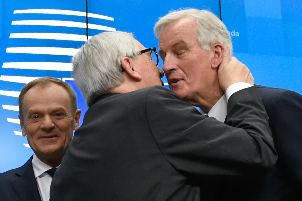 President of the European Commission Jean-Claude Juncker (C) kisses EU chief Brexit negotiator Michel Barnier (R) next to European Council President Donald Tusk (L) at the end of a press conference following a special meeting of the European Council to en